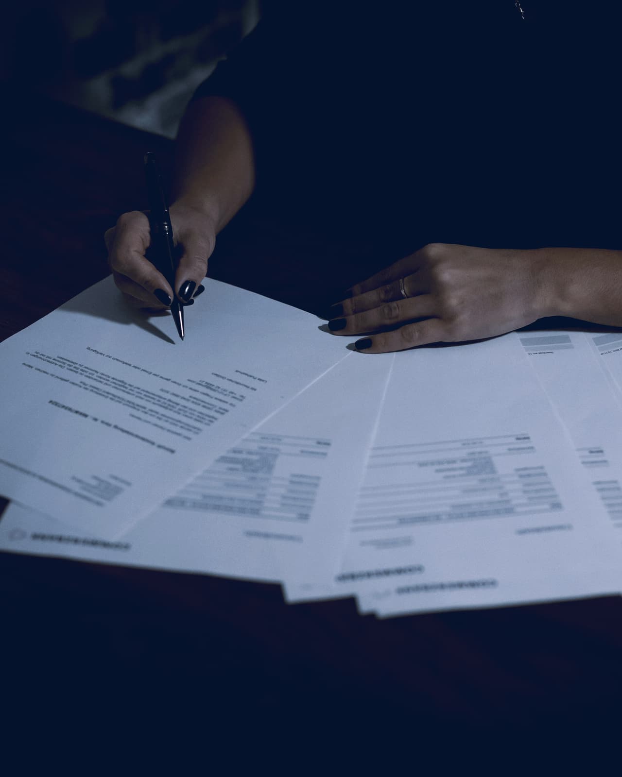 Owner working through a spread of paperwork at a desk late in the evening